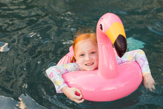 Redhead girl plays in flamingo pool float