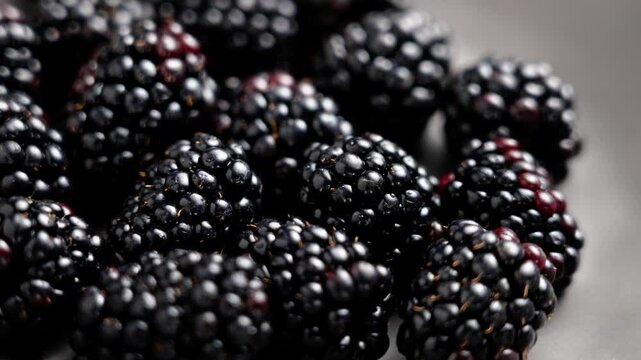 Black bramble berries in grey ceramic plate. Fresh juicy organic blackberries. Healthy ingredient. Macro. Rotation