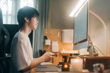Relax asian man playing game console with controller at home office
