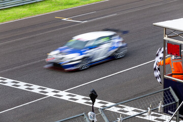 Race car crossing finish line on track and pass checkered race flag, Checkered racing finish flag...