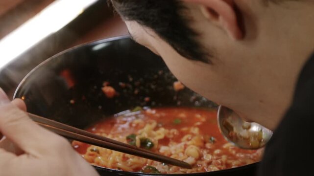 매콤한 라면이 담긴 검은 그릇에 밥을 넣는 모습