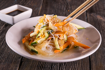 Asian Chopped Salad on wood table. Chinese food. wooden sticks, soy sauce.