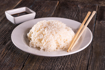 White rice in bowl on wood table. Chinese food. wooden sticks, soy sauce