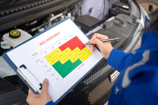 An engineer is using a pen to checking on the safety risk assessment with color matrix form to evaluate the risk level. Industrial ot business working scene, close-up and selective focus.