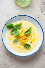 Blue and white plate with chilled gazpacho made of sweet corn, vertical shot on a beige granite background, elevated view