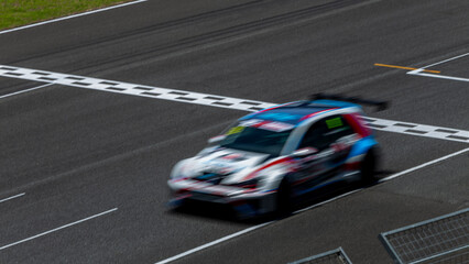 Motion blur race car racing on speed track, Car race on the international circuit race track crossing start and finish line, Race car crossing start and finish line, Target business achieve victory.