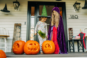 Kids in Halloween costumes on porch with carved pumpkins