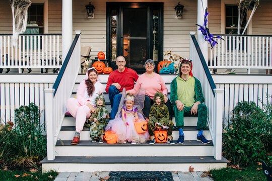 Family in Halloween costumes sitting on a decorated porch