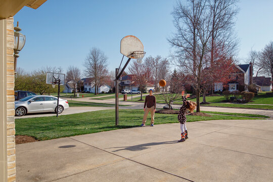 Small girl shoots basketball while father watches