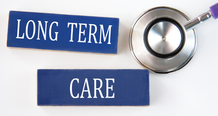 LONG TERM CARE - words on blue wooden blocks on white background with stethoscope
