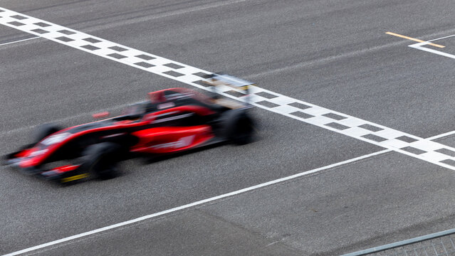 Motion blur race car racing on speed track, Car race on the international circuit race track crossing start and finish line, Race car crossing start and finish line, Target business achieve victory.