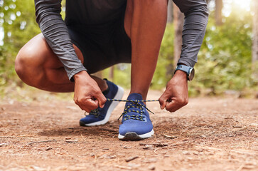Tying, shoelaces and hands of runner, outdoor and workout in woods, legs and athlete in nature for...