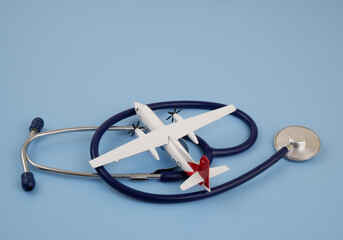 Airplane with blue stethoscope on blue background. Copy space for text.