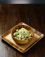 Traditional Russian Olivier Salad in Wooden Bowl on Rustic Table.