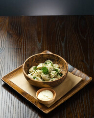 Traditional Russian Pelmeni Dumplings with Chopped Herbs and Sour Cream on Rustic Table.