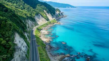 Beautiful coastal route meandering alongside a verdant cliff, with stunning views of the sparkling blue sea under clear skies