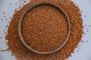 Camelina sativa seeds, camelina seeds in wooden bowl isolated on white background. Raw material for camelina oil.