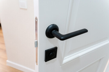 A close up of a white door with a black door handle