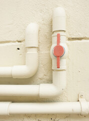 At the end of three plumbing pipes, the middle pipe has a red on-off valve. Three pipes painted...