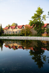 Fototapeta premium A beautiful building featuring striking red roofs is reflected in a serene body of water, creating a picturesque scene that captures the essence of nature and tranquility