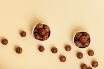 Shelled macadamia nuts in a in small white ceramic plates from above on a beige background. Tasty...