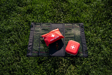 A first aid kit is sitting on top of a blanket in the grass
