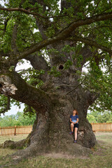 Woman leaning against a centennial tree