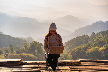 Young woman freelancer traveler working online using laptop and enjoying the beautiful nature...
