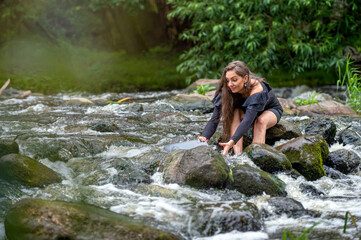 female freelancer sitting on a rock in the river and dropping her laptop into the water