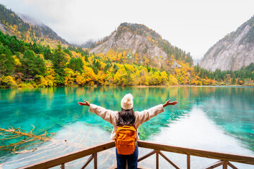 Young female tourist looking at beautiful autumn scenery landscape at jiuzhaigou national park in Sichuan, China