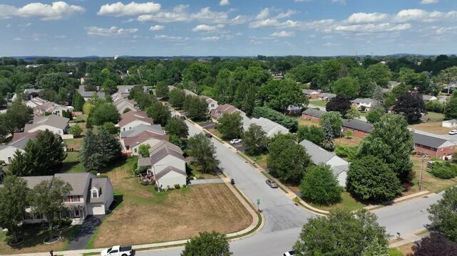 Suburban neighborhood with neatly arranged houses in Pennsylvania. Residential streets and green lawns. Green trees in summer season. Aerial rising wide shot.
