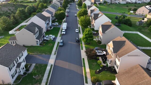 American suburb neighborhood at sunrise. Aerial drone shot of single family houses with parking cars. New modern neighborhood in suburbia. Aerial tilt up shot scene .USA retirement home
