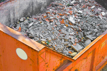 Concrete and brick rubble debris in a container box on construction site after a demolition of a...
