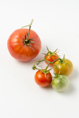 Ripe and green natural tomatoes on a white background. Close up.