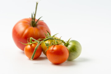 Ripe and green natural tomatoes on a white background. Close up.