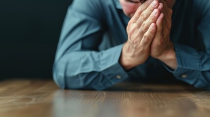 Obraz premium A contemplative moment of a man with hands clasped, reflecting deep thoughts or emotions during a quiet, introspective time.