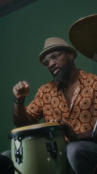 Vertical shot of African American conga drummer discussing rhythmic pattern with other musician while rehearsing new composition