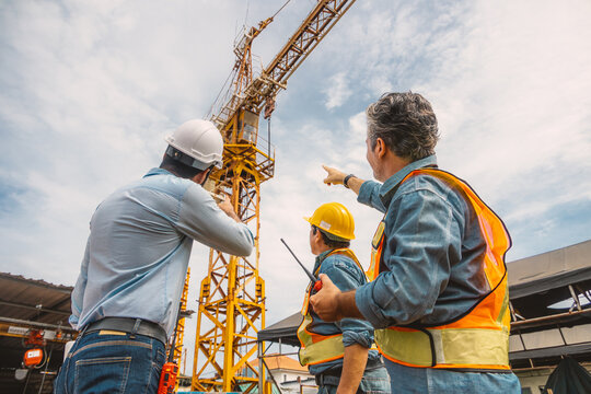 Professional construction engineer workers team working together control operating Crane tower at building project construction site.