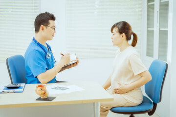 A male Asian pediatrician in a white lab coat conducts a prenatal checkup for a middle-aged pregnant woman, focusing on maternal and fetal health, offering expert care and guidance.