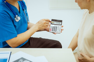 A male Asian pediatrician in a white lab coat conducts a prenatal checkup for a middle-aged...
