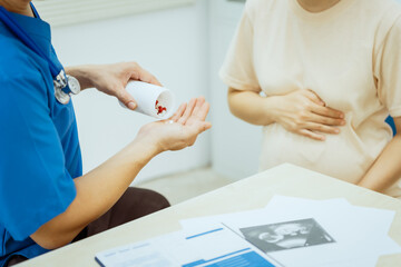 A male Asian pediatrician in a white lab coat conducts a prenatal checkup for a middle-aged pregnant woman, focusing on maternal and fetal health, offering expert care and guidance.