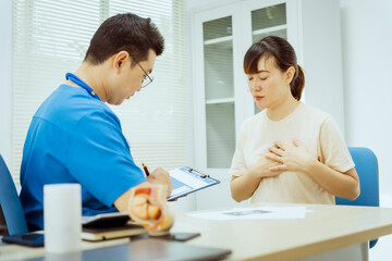 Obraz premium A male Asian pediatrician in a white lab coat conducts a prenatal checkup for a middle-aged pregnant woman, focusing on maternal and fetal health, offering expert care and guidance.