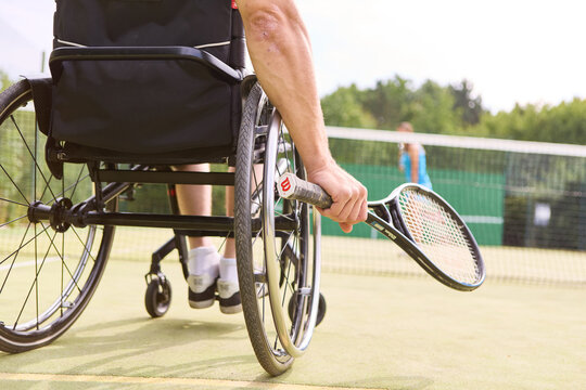 Athlete in wheelchair playing tennis on outdoor court, showcasing determination and skill