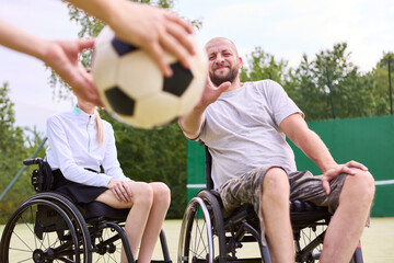 Obraz premium People in wheelchairs actively participating in a sport, sharing a ball on a sunlit court