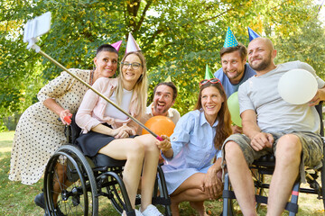 Celebrating outdoors with friends, including wheelchair user and birthday props