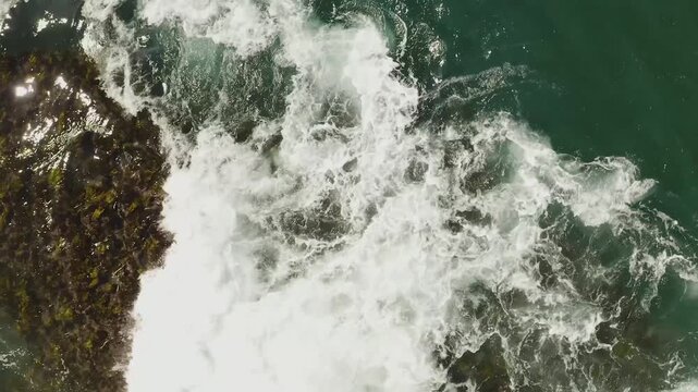 Ocean waves breaking over coral reef, top down aerial close up