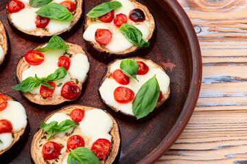 Italian mini pizza . Aubergine (eggplant ) with mozzarella cheese and basil . On rustic background
