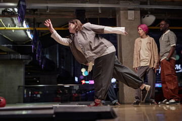 Friends enjoying an evening of bowling in a modern indoor alley lit by colorful lights creating a vibrant atmosphere emphasizing their excitement and camaraderie