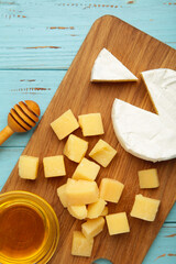 Honey with camembert and parmesan cheeses on cutting board. Vertical photo