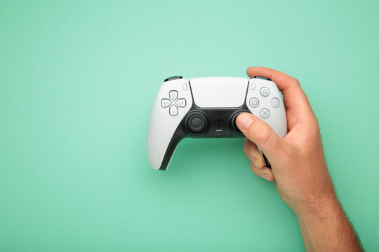 Mykolaiv, UKRAINE - July, 2024: Female hand holding a new Sony Playstation 5 DualSense white controller on mint background. Space for text